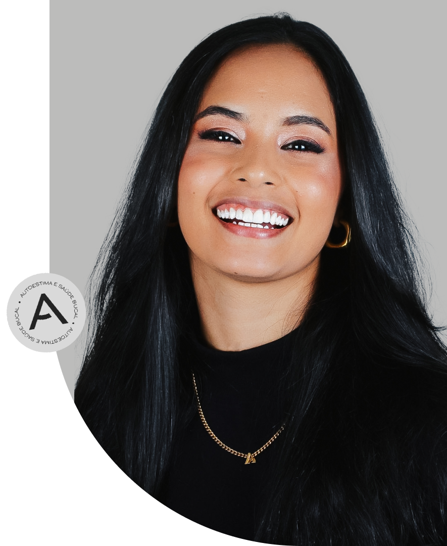 Mulher em torno dos 25 anos, cabelos pretos, blusa preta, utilizando colar e sorrindo para a foto.